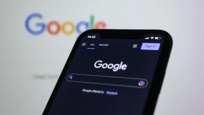 Smartphone met de Google zoekpagina in donkere modus voor een wazig Google logo op de achtergrond.