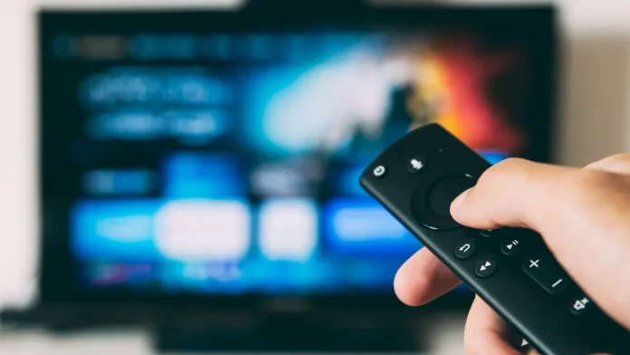 Hand met afstandsbediening voor een smart-tv met Google interface voor het streamen van films.