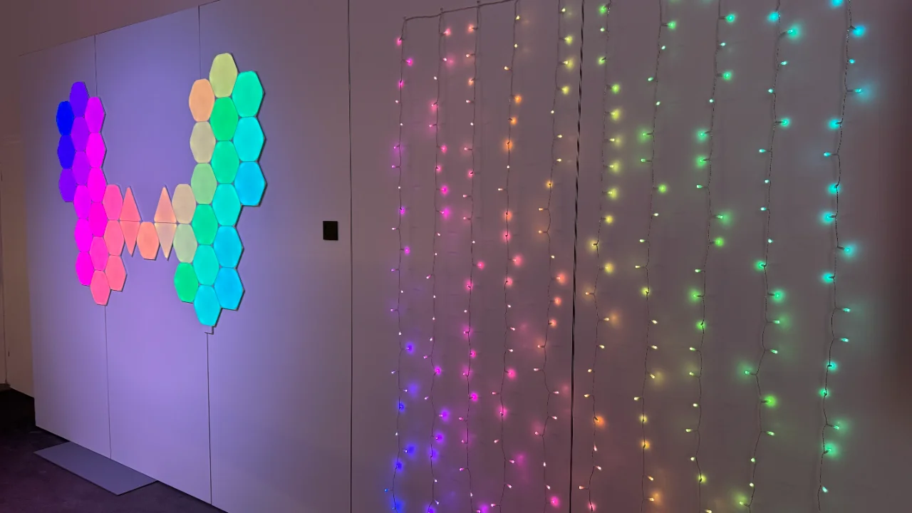 Hexagonal LED wall panels and curtain string lights displaying a vibrant rainbow hue gradient.
