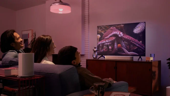 Gezin geniet van een film met sfeervolle Hue Sonos verlichting en geluid in de woonkamer.