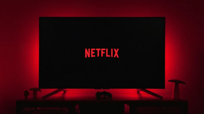 Netflix-logo op een LG TV met rode sfeerverlichting in een donkere kamer.