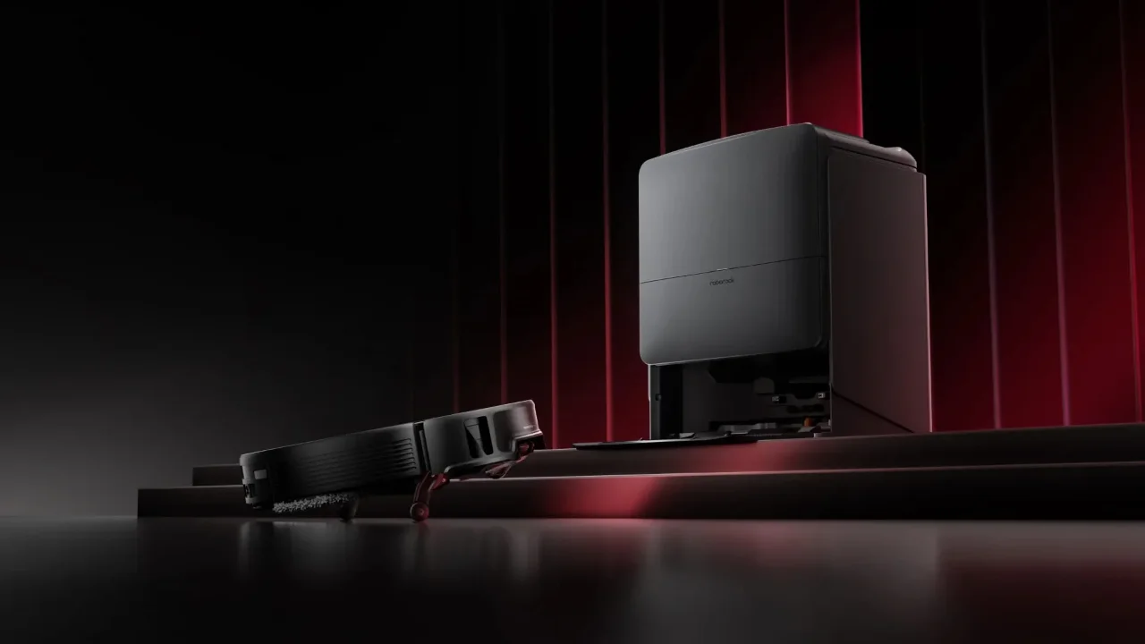 Sleek black Roborock robot vacuum and docking station on a dark stage with dramatic red lighting.