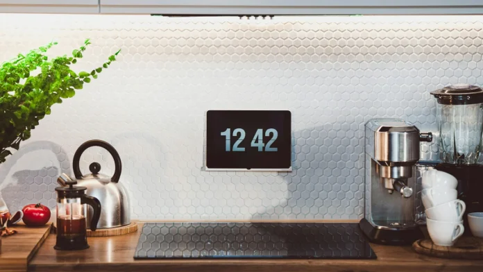 Moderne keuken met smarthome tablet aan de wand, espressoapparaat en waterkoker op een houten werkblad.