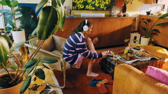 Vrouw lakt haar nagels met een witte Sonos hoofdtelefoon op in een sfeervolle, groene woonkamer.