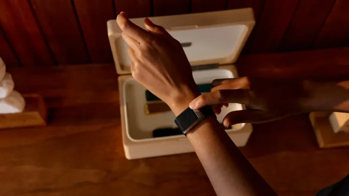 Persoon draagt een zwarte Whoop fitness tracker om de pols bij een houten opbergdoos.