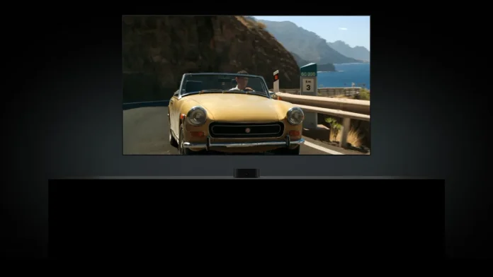 Apple TV 4K aan een tv met een film van een gele cabrio op een kustweg.