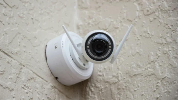 Witte draadloze beveiligingscamera met antennes gemonteerd op een gestucte muur.