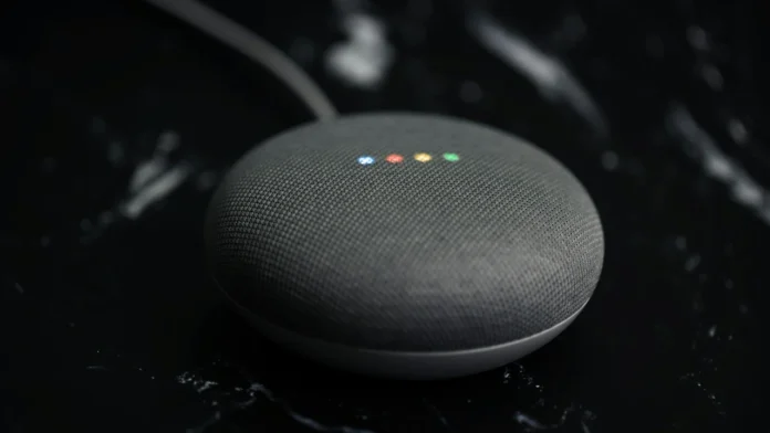 Een Google Home Mini speaker met vier gekleurde lampjes op een donkere ondergrond