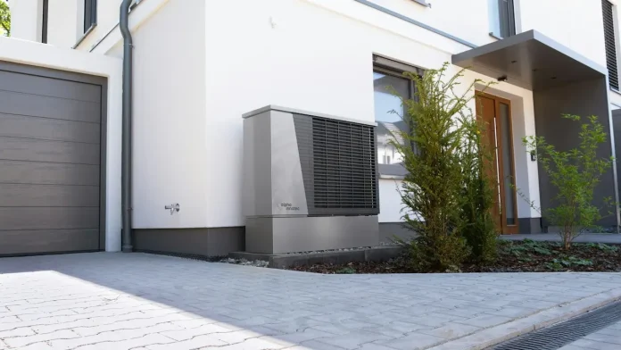 Moderne woning met de buitenunit van een lucht-waterwarmtepomp naast de garage en de voordeur