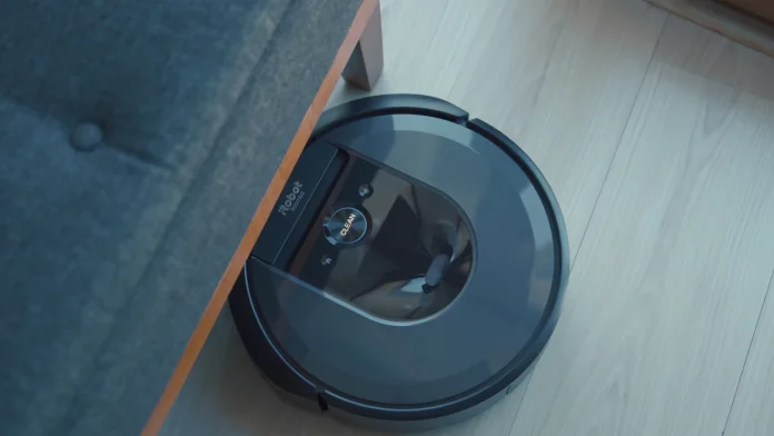 iRobot Roomba rijdt onder een bank over een lichte houten vloer