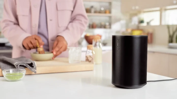 Zwarte Sonos speaker op een aanrecht in een moderne keuken tijdens het koken.