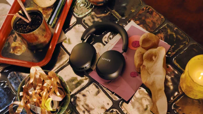 Zwarte Sonos Ace hoofdtelefoon op een artistieke tafel met decoratie en een brandende kaars.