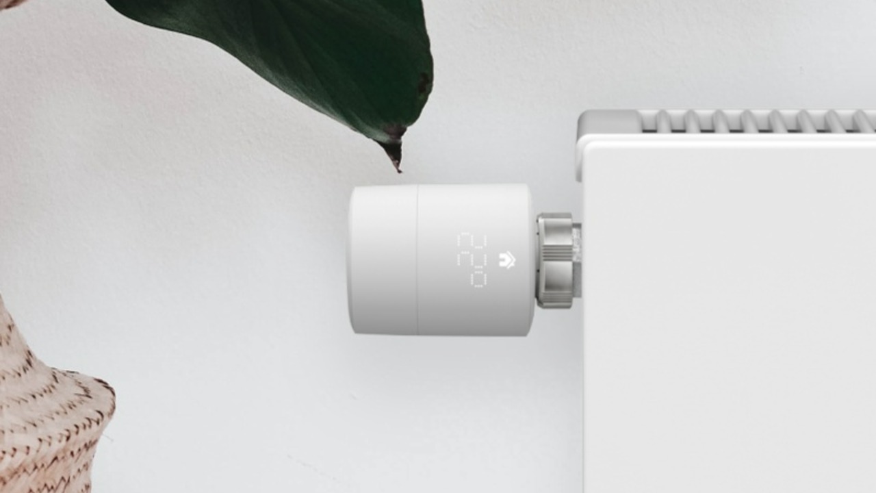 Witte tado slimme radiatorknop toont 22.0 graden op een radiator, zo kun je per kamer stookkosten verlagen