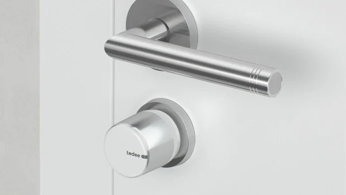 tedee Lock GO 2 smart lock op een witte deur naast een deurkruk