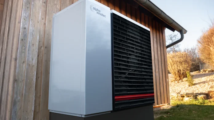Buitenunit van een warmtepomp tegen een houten gevel